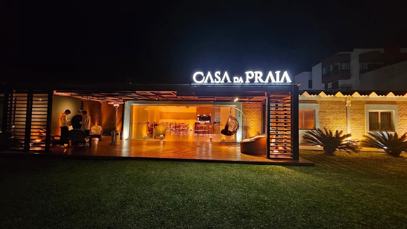 Fachada iluminada à noite, com o letreiro aceso